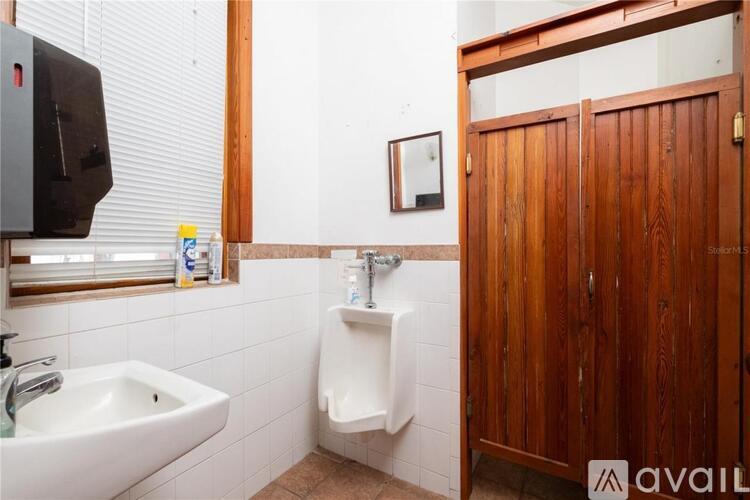 A bathroom with a sink, urinal, and wooden door.