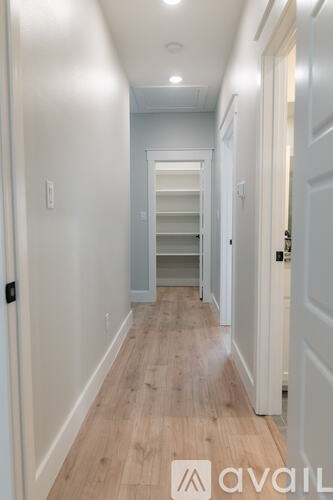 A hallway with a row of shelves and a door on the right.