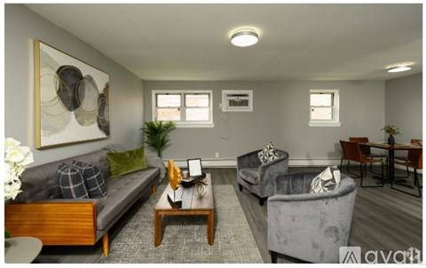 A living room with a grey sofa, a grey armchair, a wooden coffee table, and a painting on the wall.