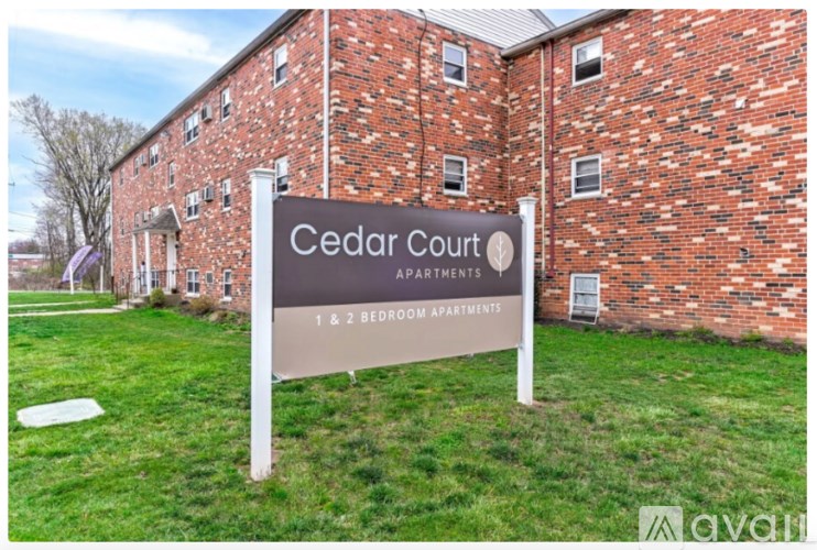 A sign in front of a brick building that says Cedar Court Apartments.