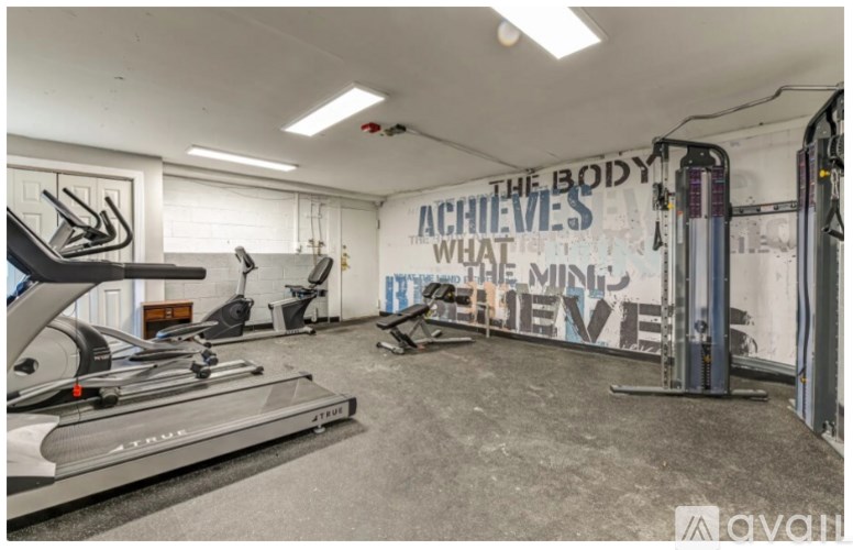 A gym with a wall mural that says "The Body Achieves What The Mind Imposes".