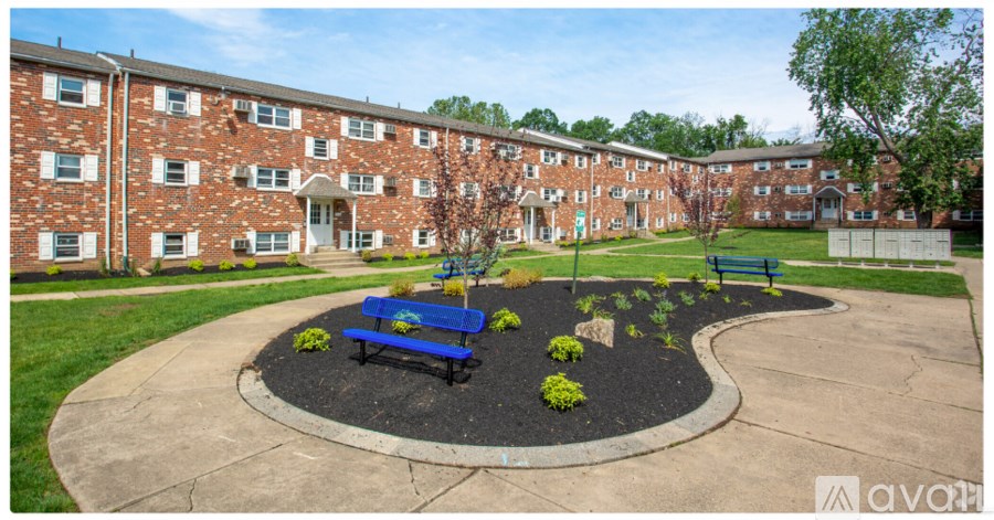 A large brick building with a blue bench and a small garden in front.