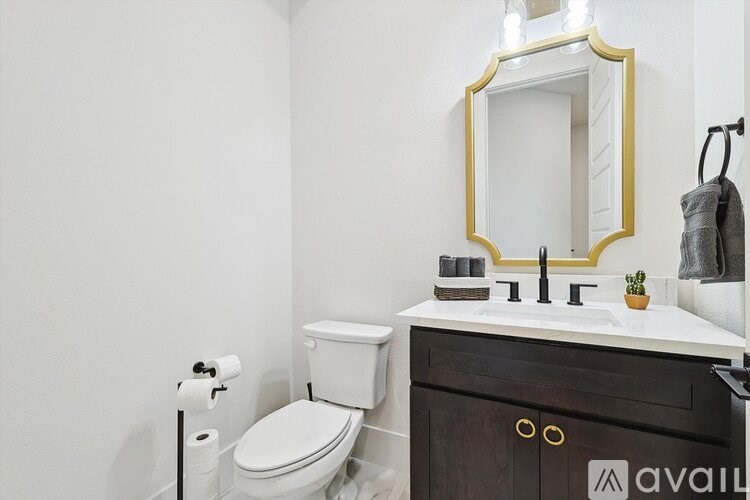 A bathroom with a toilet, sink, and mirror.