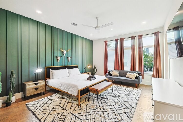 A bedroom with a bed, a couch, and a rug.