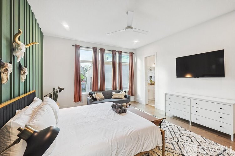 A bedroom with a white bed and a black and white rug.