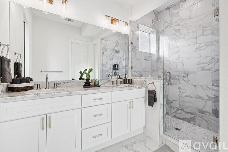 A bathroom with marble tiles and white cabinets.