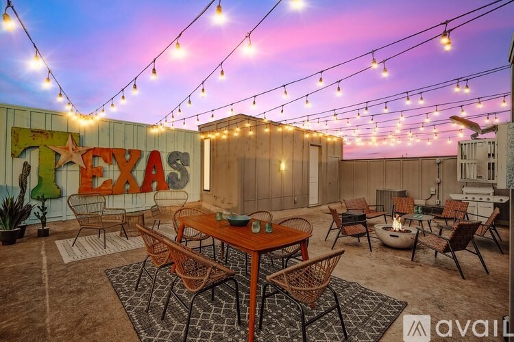 A patio with a table and chairs under string lights.