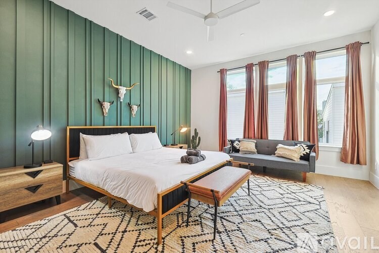 A bedroom with a bed, a couch, and a rug.