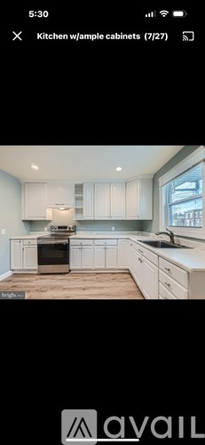 A kitchen with white cabinets and a wooden floor.