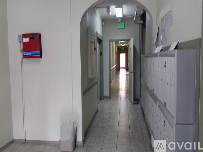 A long hallway with a red box on the wall and a green exit sign above.
