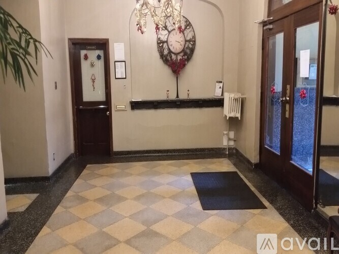 A hallway with a black and white checkered floor, a chandelier, and a wall clock.