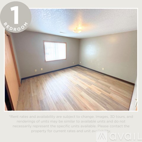 A bedroom with a window and wooden flooring.