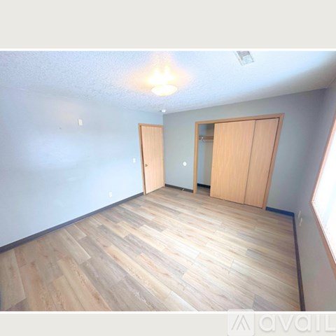 A room with wooden flooring and two doors.