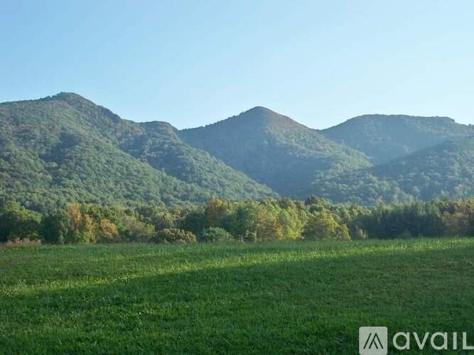 A mountain range with a green field in the foreground.