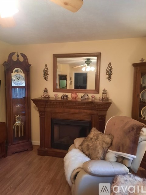 A living room with a brown leather chair and a wooden fireplace.