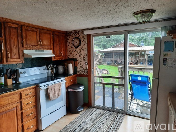 A kitchen with a stove, refrigerator, and a view of a backyard.
