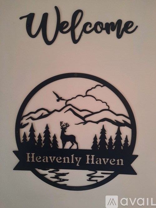 A wooden sign that says "Welcome to Heavenly Haven" with a mountain scene and a deer.