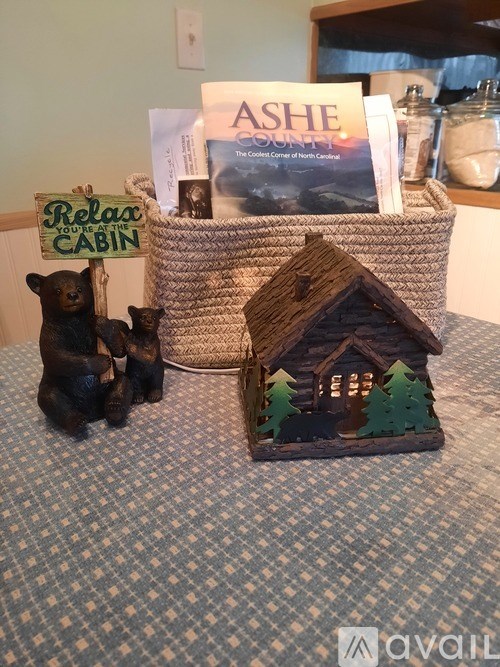 A small house with trees and a bear figurine sits on a table.
