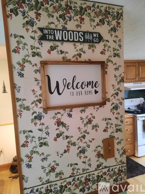 A wall with a floral pattern and a wooden frame that says "Welcome to our home".