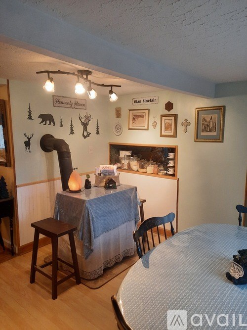 A dining area with a table and chairs and a bear decoration on the wall.