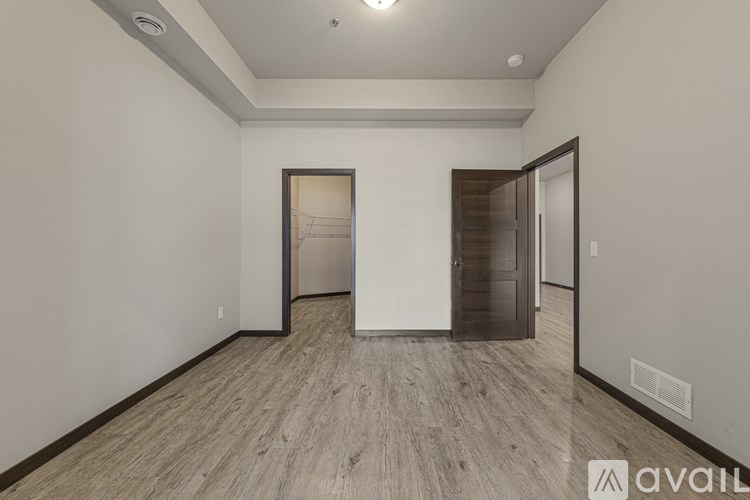 A room with wooden flooring and two doors, one of which is open.
