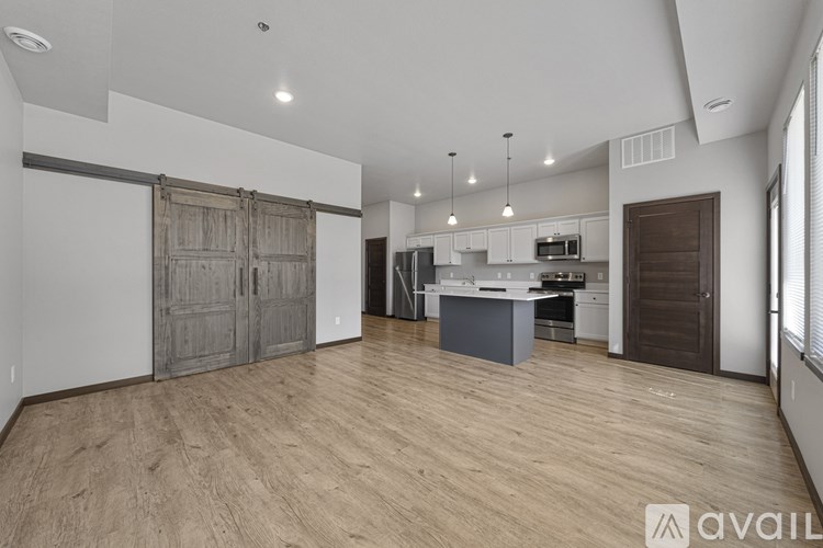A spacious kitchen and living area with wooden flooring and white walls.