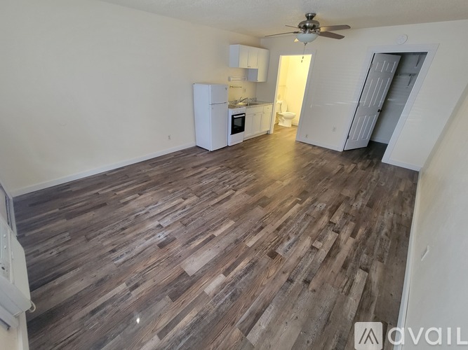 A room with wooden flooring and a white refrigerator.
