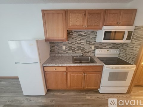 A kitchen with wooden cabinets and a stone backsplash.