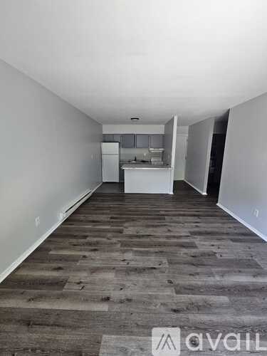 A long, empty hallway with a kitchen visible in the distance.