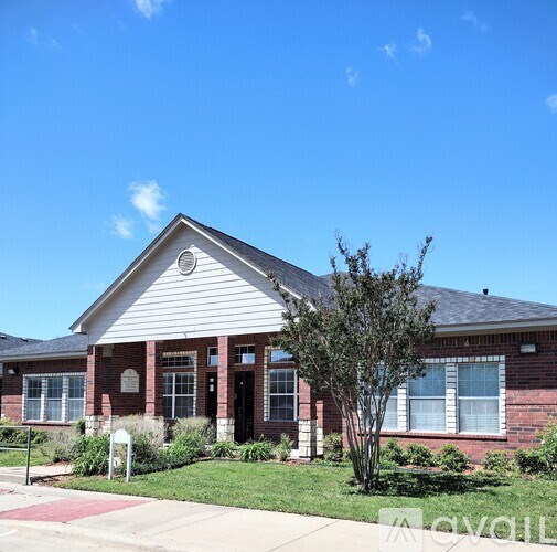 A red brick house with a white roof and a tree in front.