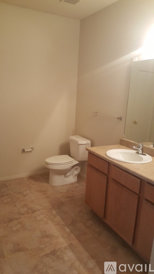 A bathroom with a toilet, sink, and wooden cabinets.