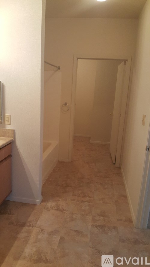 A hallway with tiled flooring and a door at the end.