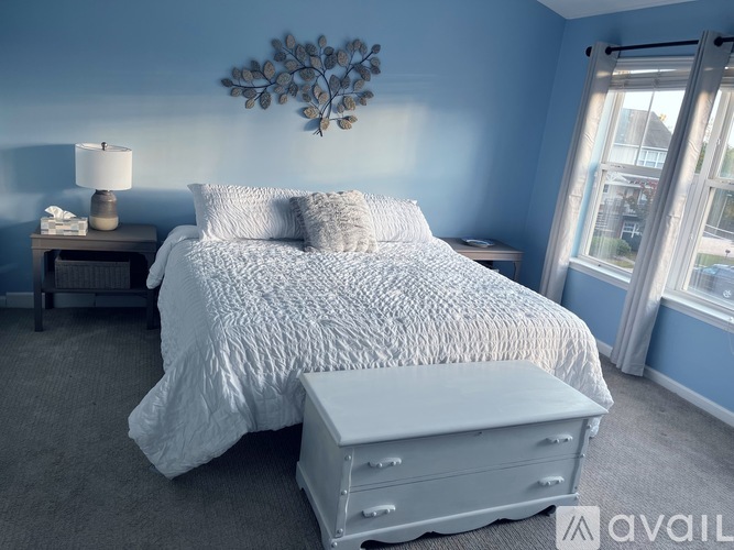 A bedroom with a large bed and a white ottoman.