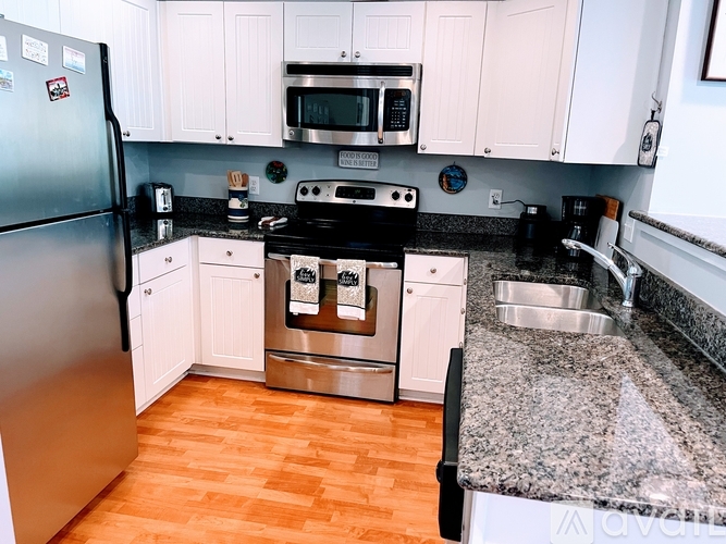 A kitchen with a granite counter top and wooden floors.