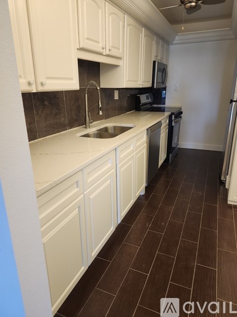 A kitchen with white cabinets and brown tile flooring.