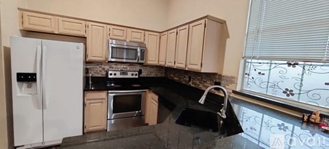A kitchen with black countertops and white appliances.