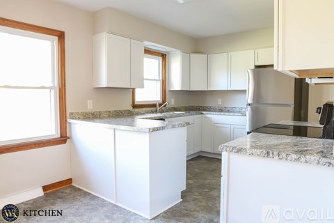 A kitchen with white cabinets and a marble countertop.
