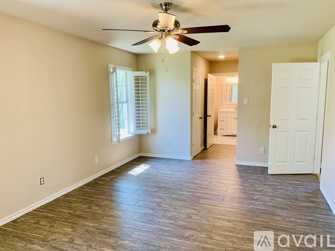A spacious room with a ceiling fan and wooden flooring.
