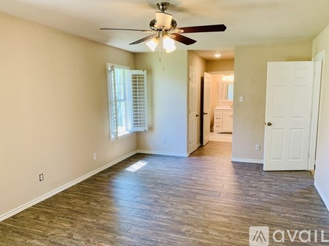 A spacious room with a ceiling fan and wooden flooring.