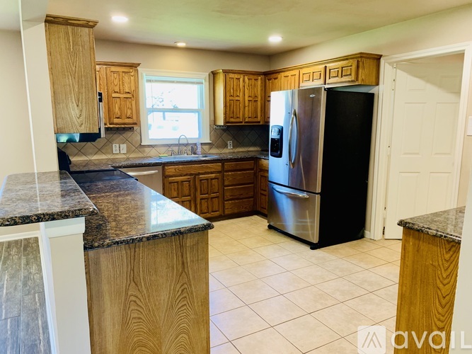 A kitchen with wooden cabinets and a black refrigerator.