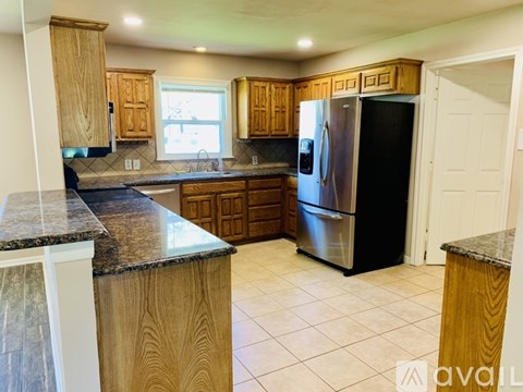 A kitchen with wooden cabinets and a black refrigerator.