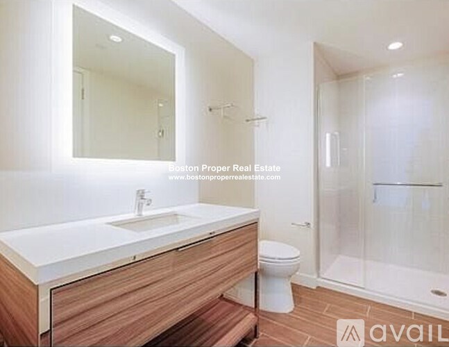 A modern bathroom with a wooden vanity and white sink.