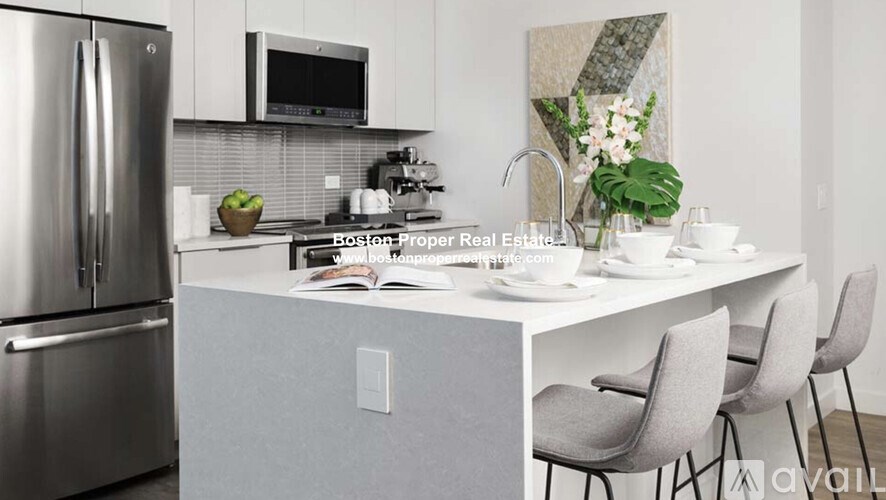 A modern kitchen with a stainless steel refrigerator, a microwave above the stove, and a breakfast bar with chairs.