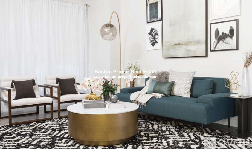 A living room with a blue couch, a coffee table, and a white chair.