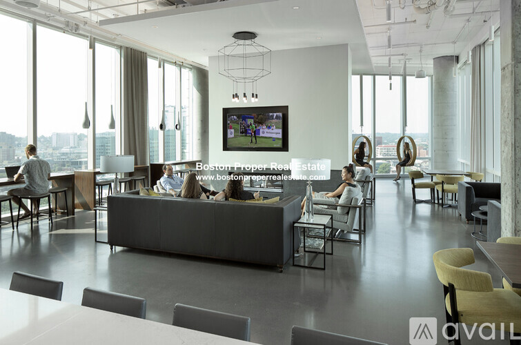 A modern office space with people working on computers and a large screen displaying a video.