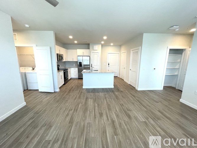 A spacious living room with a kitchen in the background.