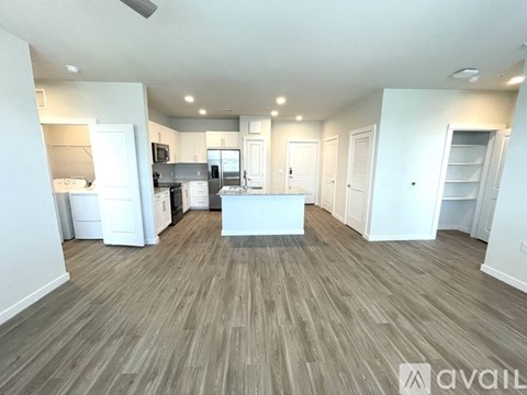 A spacious living room with a kitchen in the background.
