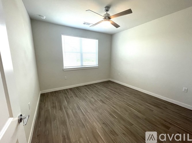 A room with a ceiling fan and wooden flooring.
