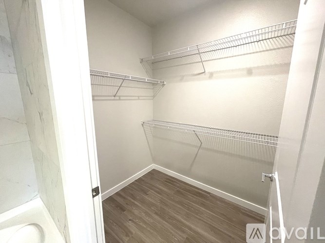 A walk-in closet with white walls and wooden floors.