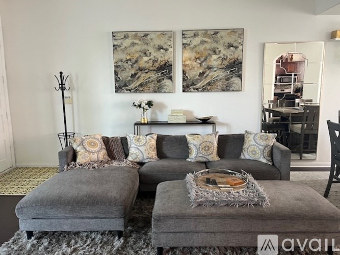 A living room with a grey couch and two grey ottomans.